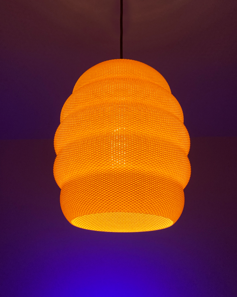 A glowing orange beehive-shaped pendant light hangs from a black cord against a warm-toned background.