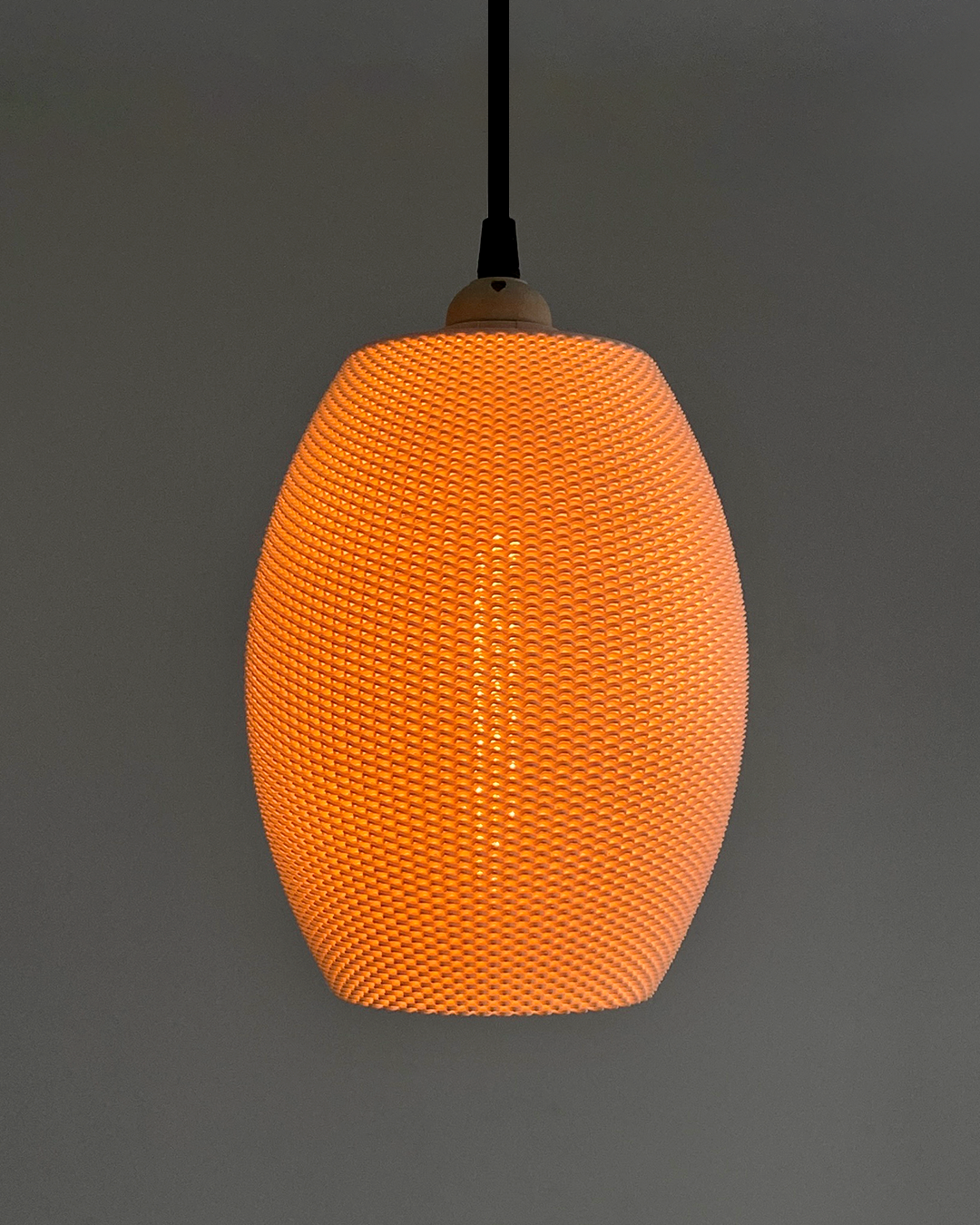 Close-up view of the Ovo Lampshade in orange, with a soft light emission, highlighting its unique texture and design.