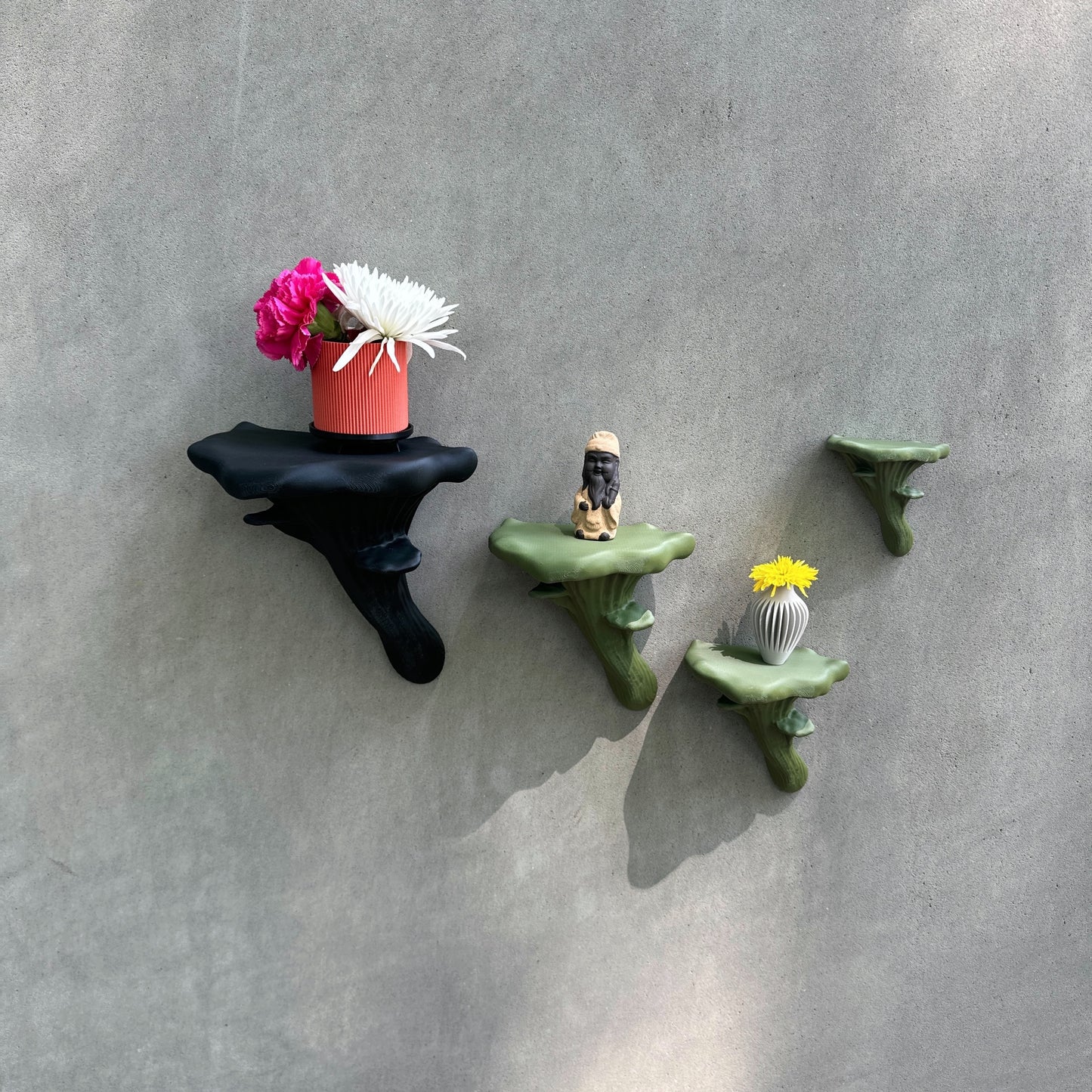 Stylish collection of black and green Oyster Floating Shelves adorned with potted flowers and decorative figurines, ideal for creative home decoration.