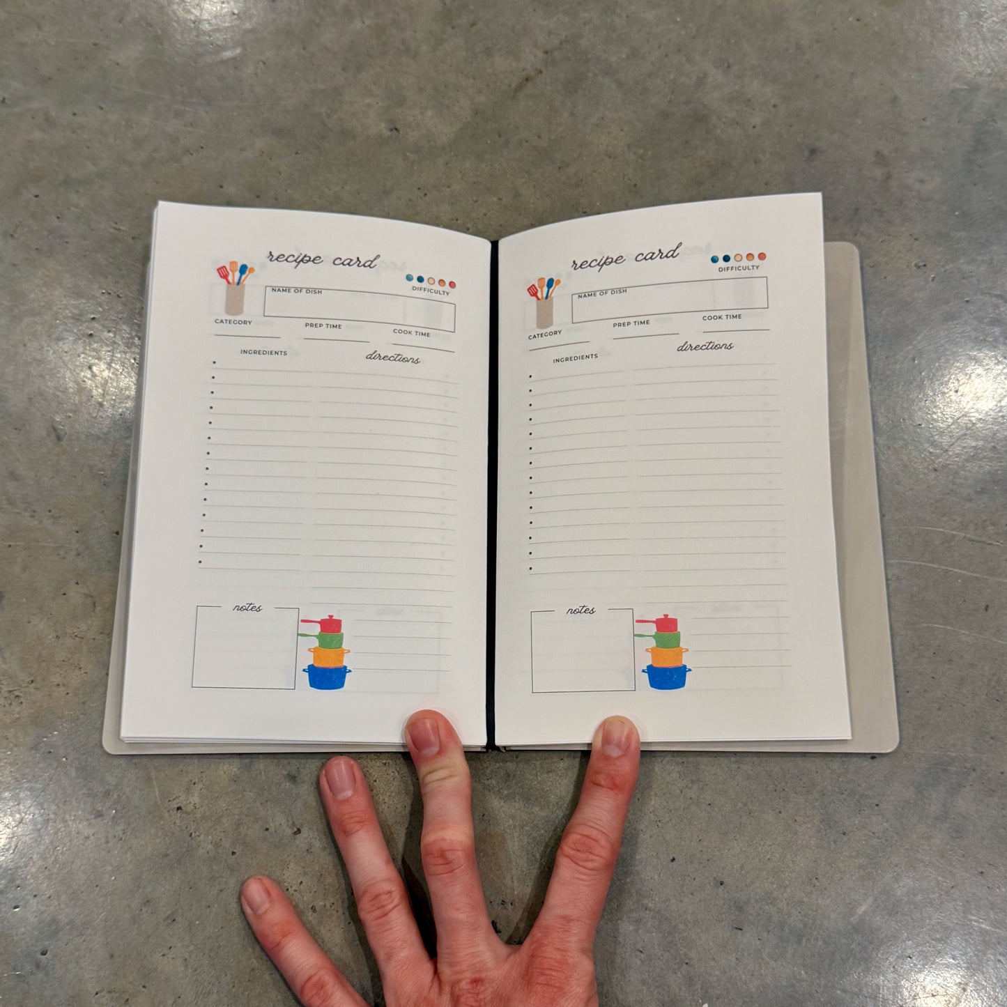 Two open pages of the 'I Am Writing My Own Cookbook' recipe book displaying structured recipe cards with sections for ingredients and directions, ideal for organizing favorite dishes.