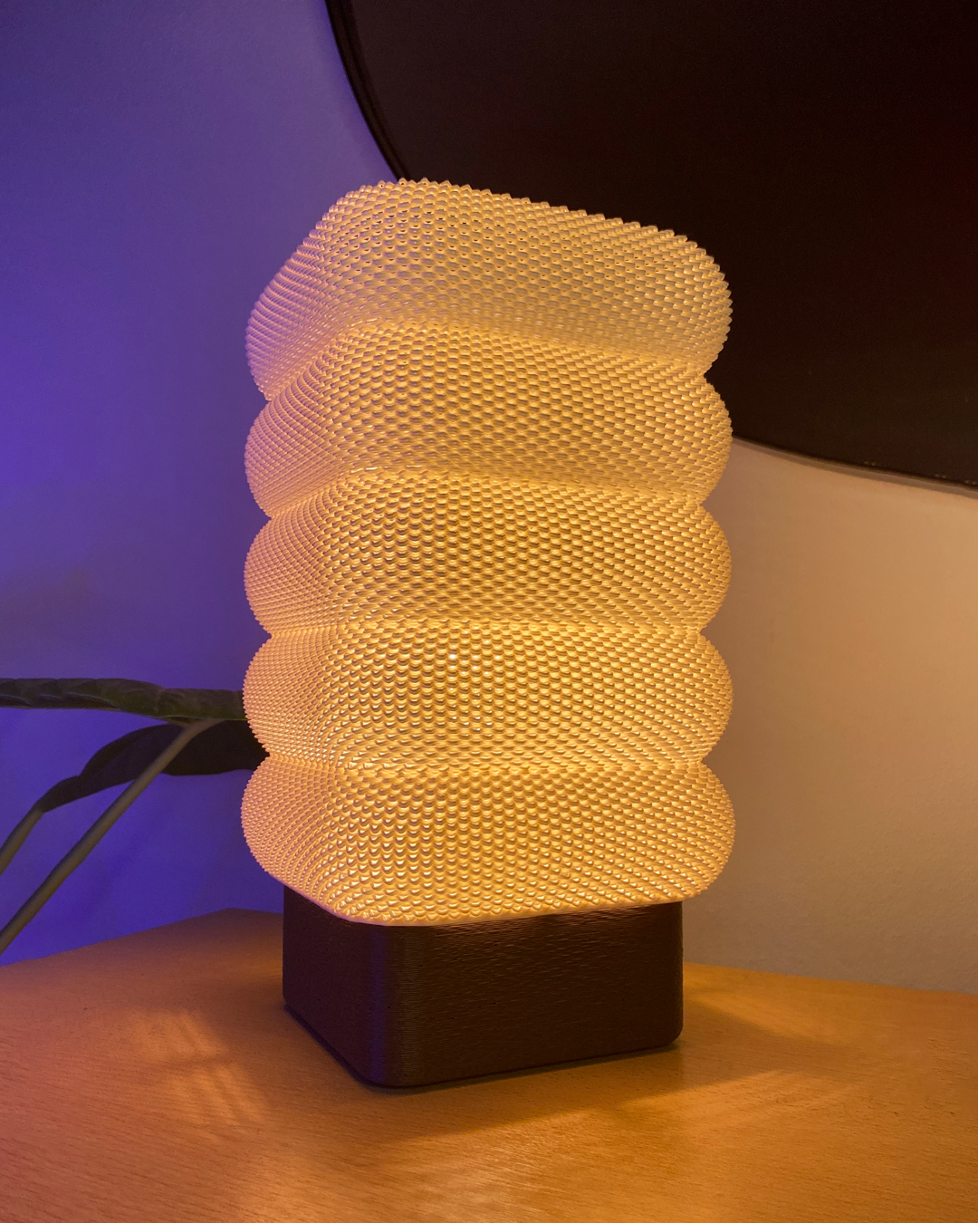 SARA Table Lamp beautifully lit in a cozy setting, with warm light highlighting its modern layered texture on a wooden table.