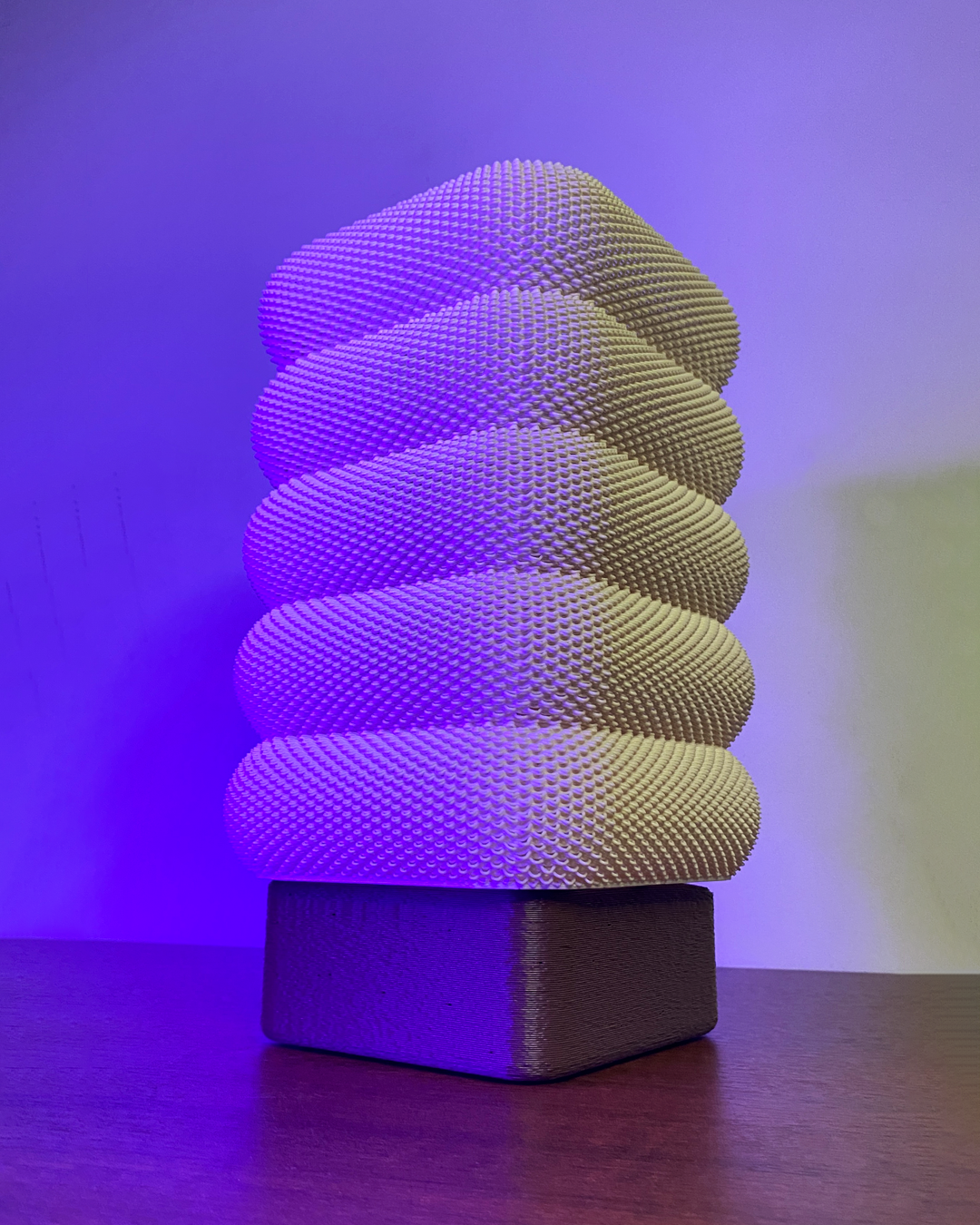 SARA Table Lamp with elegant white textured design, illuminated under a purple light, highlighting its contemporary aesthetic.