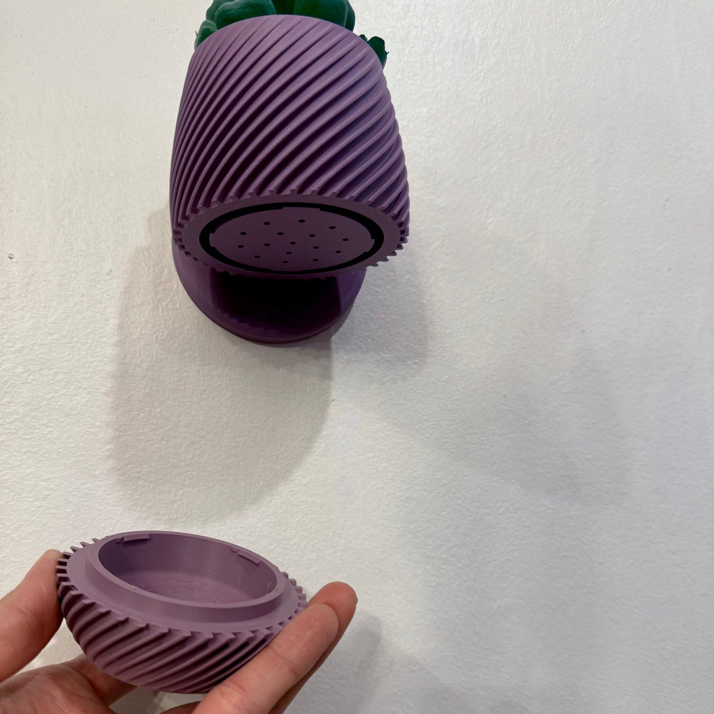 A a detached drip tray from a modern, wall-mounted planter with a unique spiral design.