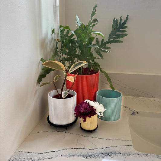 Modern ribbed planter with stand – Stylish ceramic planter featuring a ribbed texture and sleek black stand, perfect for adding a contemporary touch to any space. Available in rich marble tones.