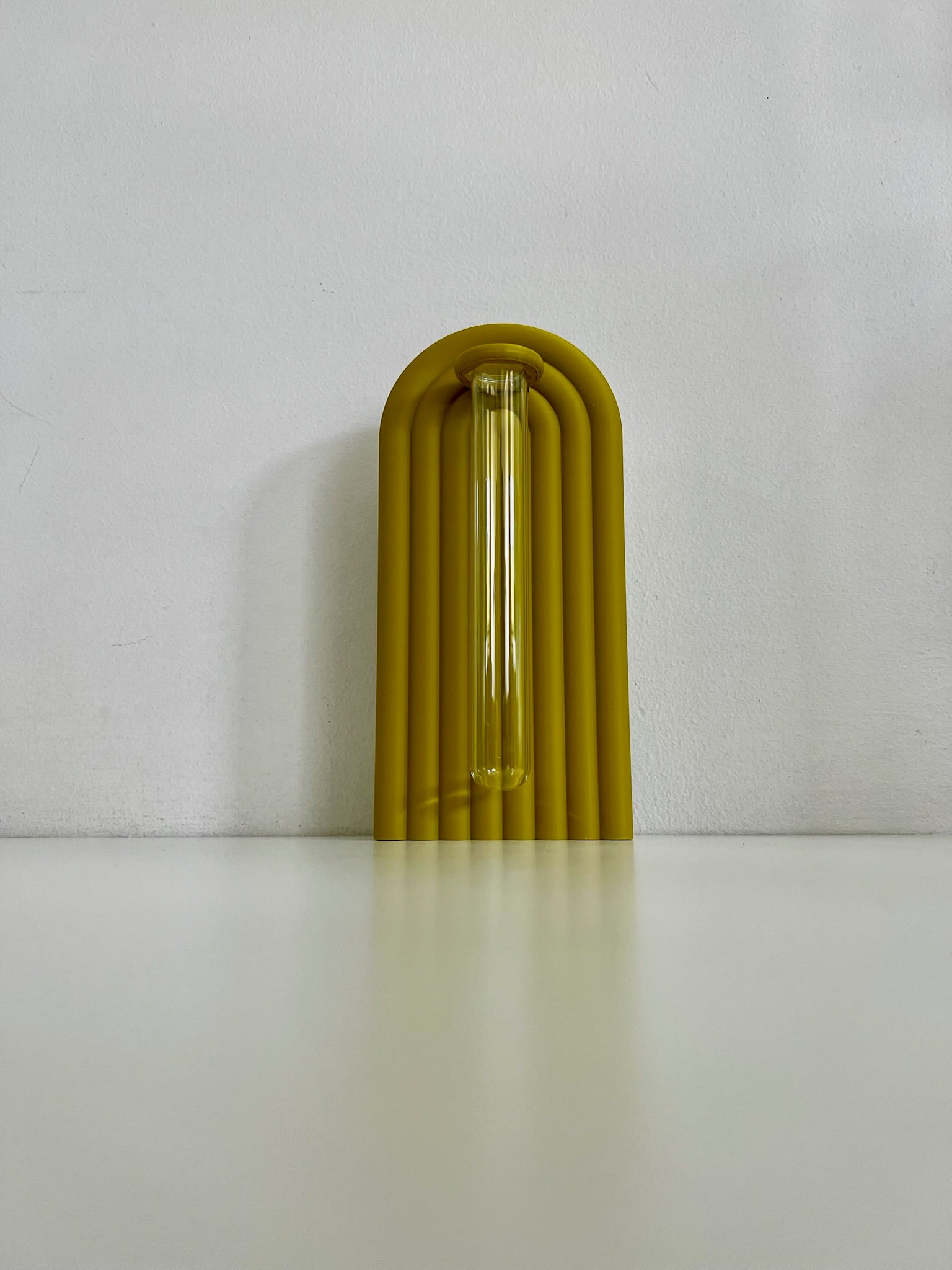 Sleek yellow propagation bookend, featuring a glass tube for plant propagation against a plain backdrop.