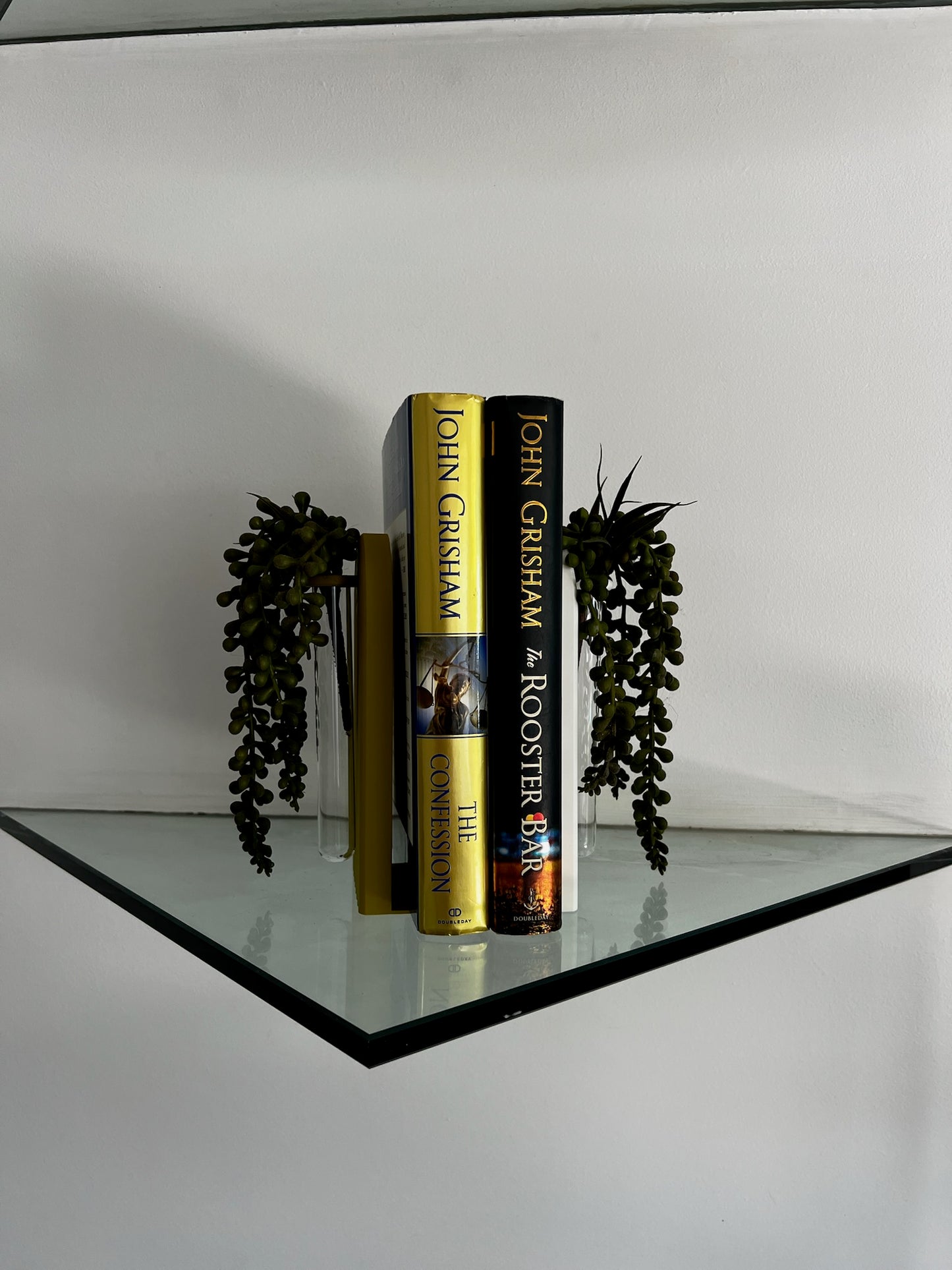 Eye-catching propagation bookend with a clear glass tube holding vibrant plant cuttings, displayed on a desk.