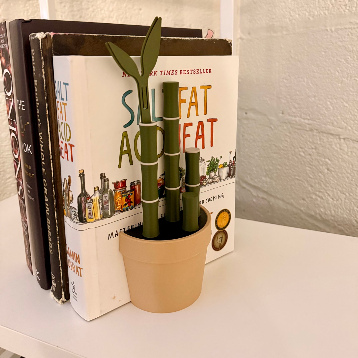 Stylish Bambu Plant Bookends with integrated leafy bookmarks, supporting books on a shelf and featuring a bamboo-inspired design.