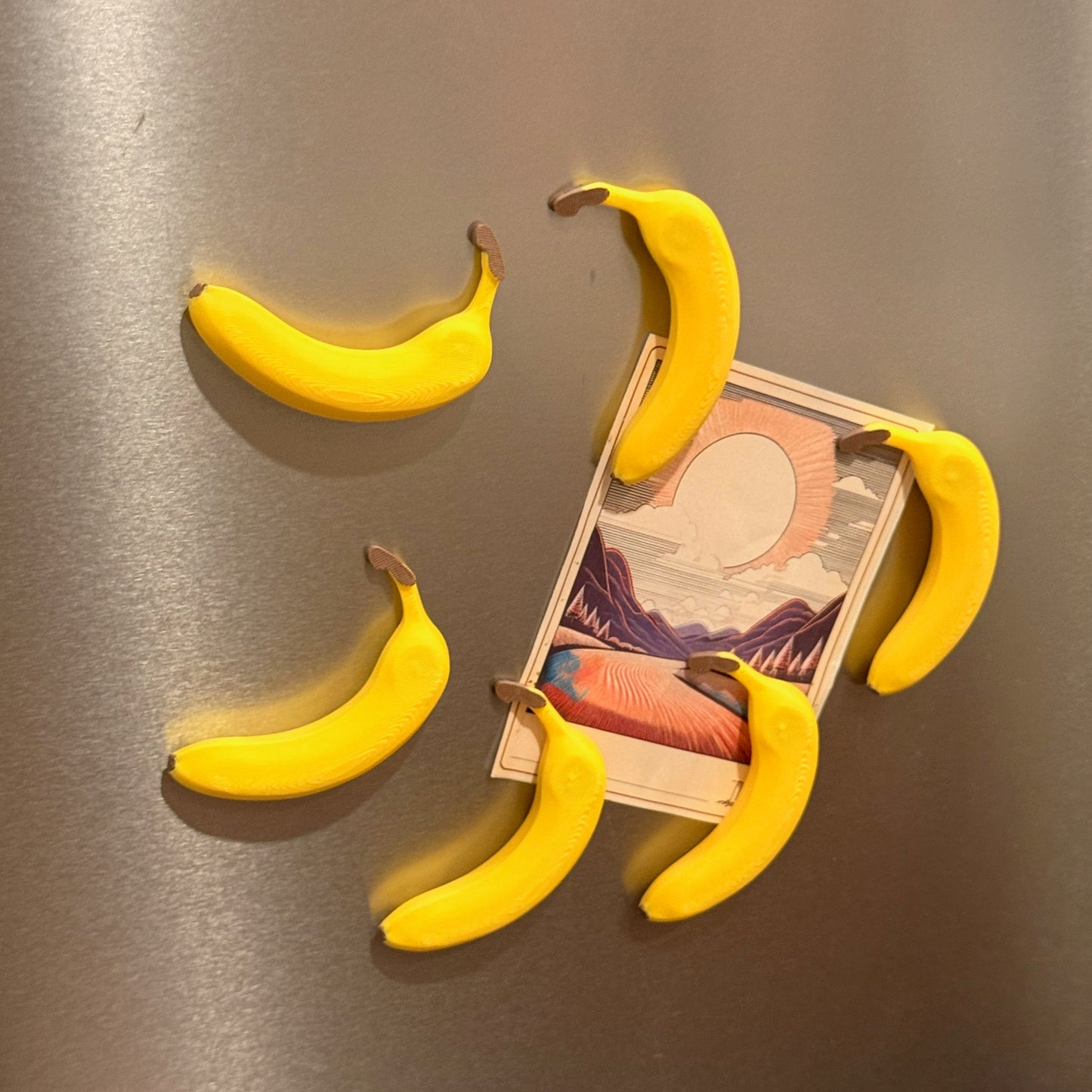 Close-up view of Stacked Banana Fridge Magnets - Set of 6 holding a note on a metallic surface, highlighting their fun design and strong magnetic hold.