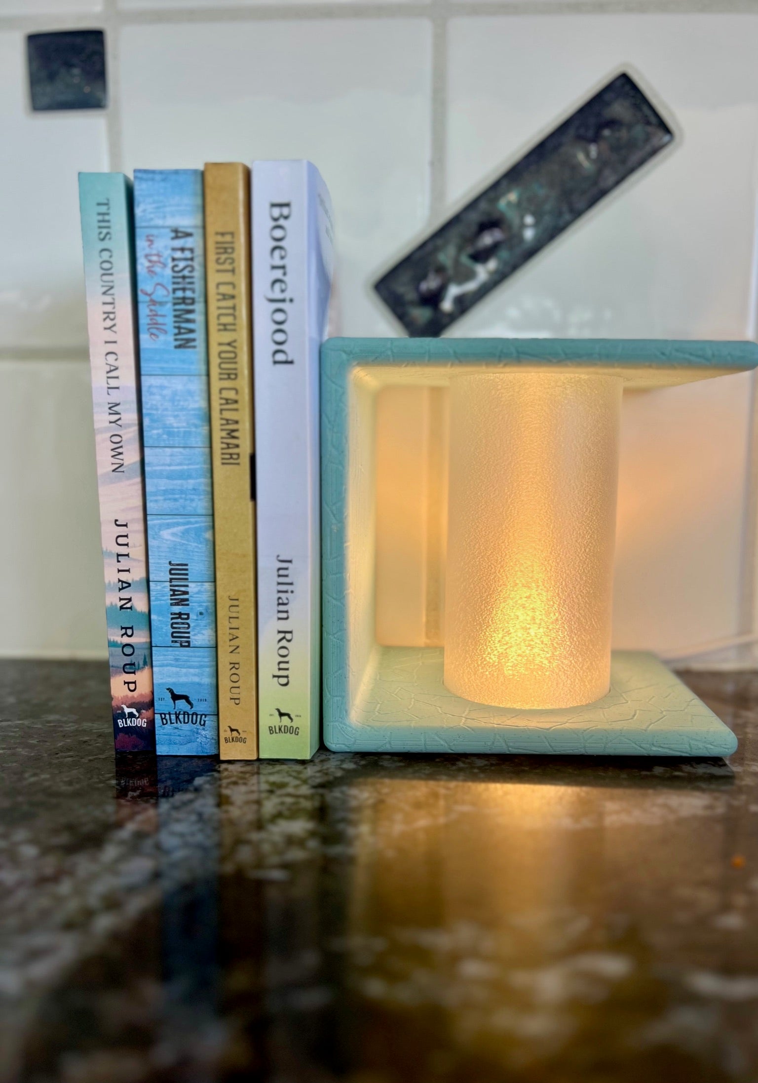 Ancient Marble Lighted Bookend highlighted with gentle lighting, positioned next to a collection of stylish books in a cozy kitchen setting.