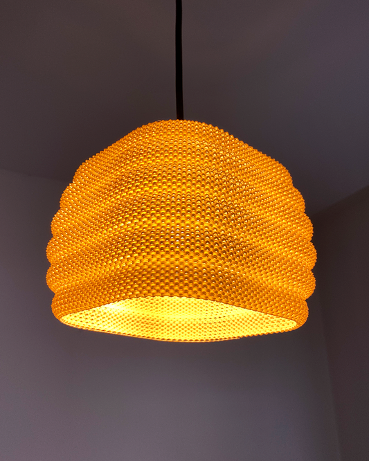 Daira Lampshade in vibrant orange, showcasing a sophisticated woven texture that creates elegant shadows when illuminated.