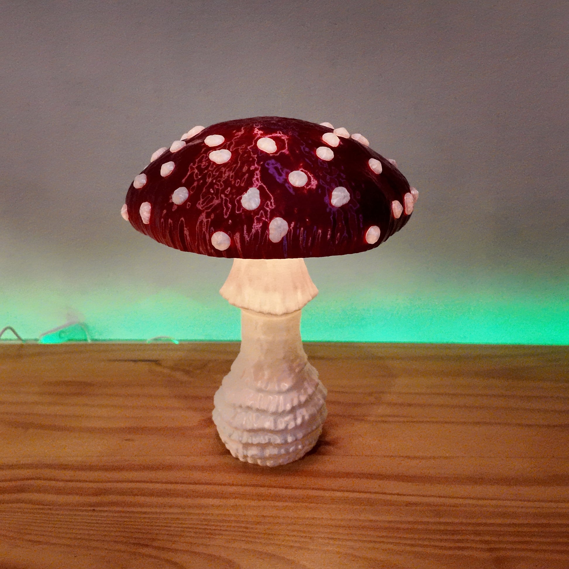 A red Amanita fungi lamp with glowing accents, positioned elegantly on a wooden table, adding charm to the decor.