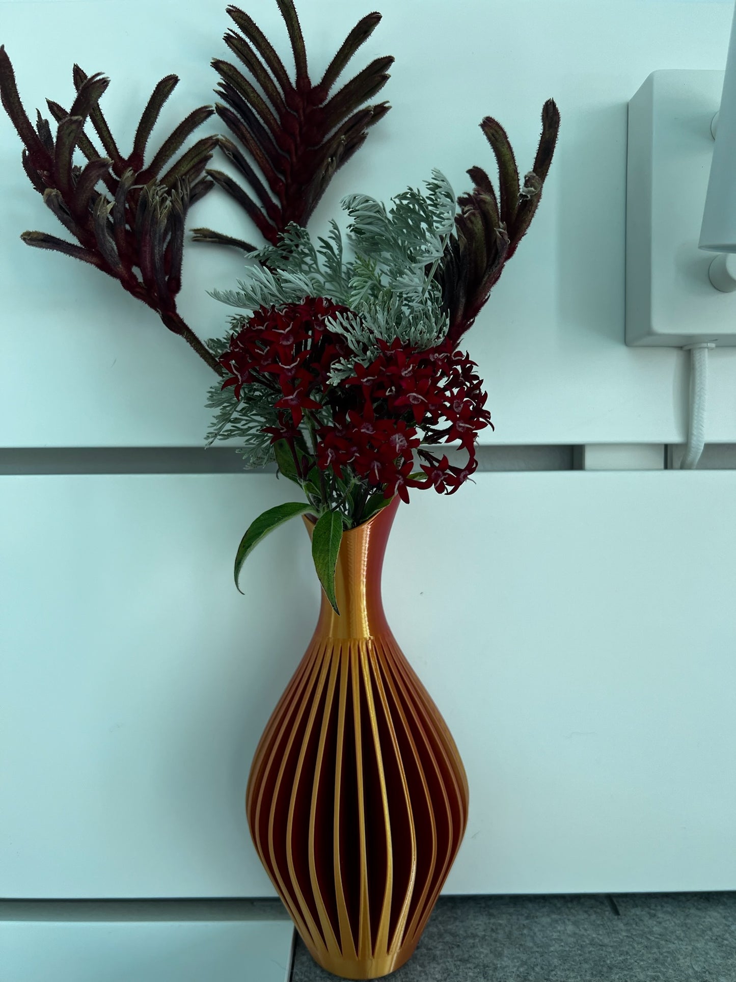 Captivating arrangement of flowers in a grey wall vase, providing stylish decor for home interiors.