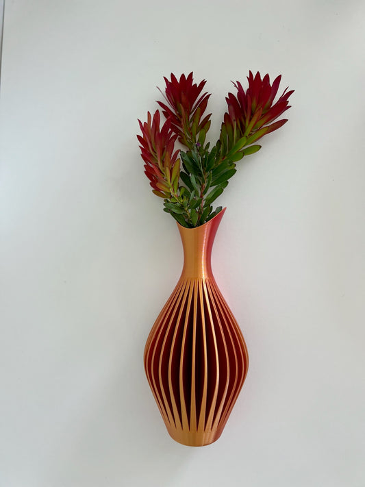 Modern dual shimmering wall vase in orange and red, showcasing floral arrangement with vibrant greenery.