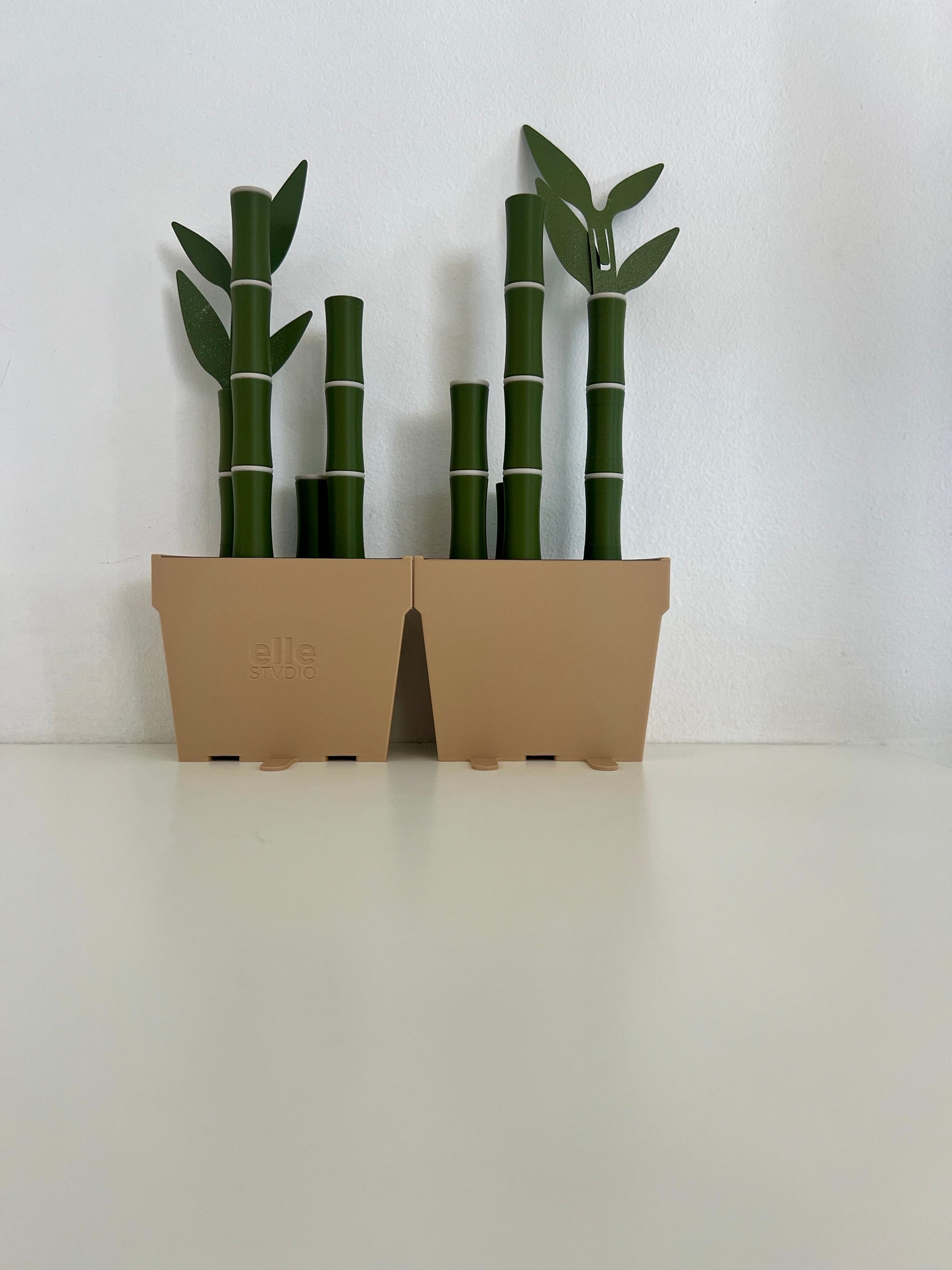 Two potted bamboo bookends side by side, featuring vibrant green bamboo and leaves, set against a clean white background for a chic look.