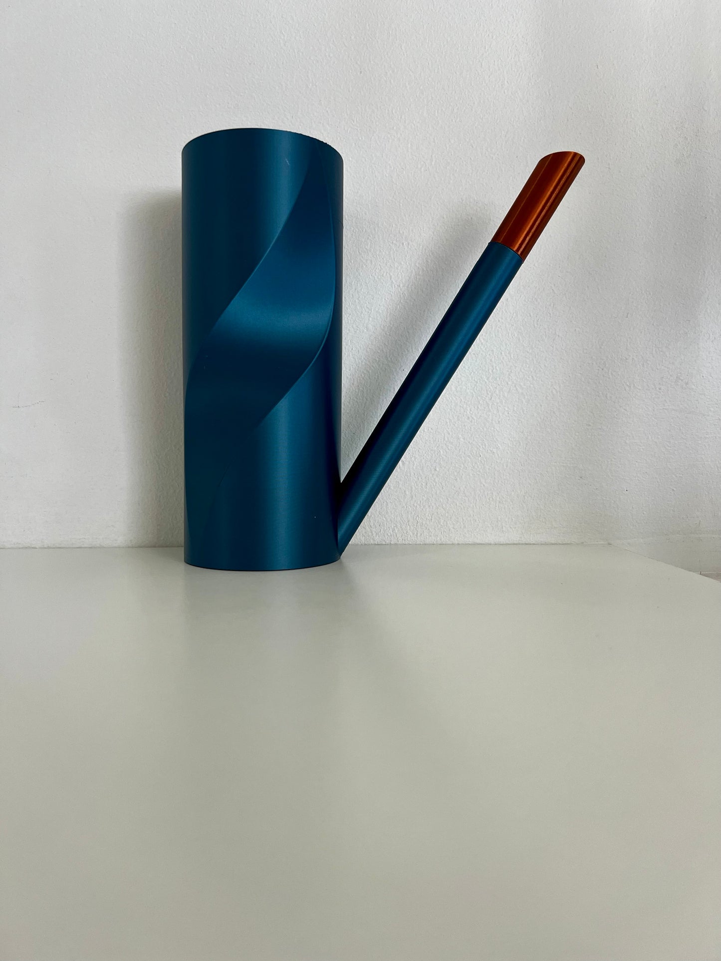 A stylish cobalt blue watering can paired with interchangeable nozzles, displayed on a minimalist grey background.