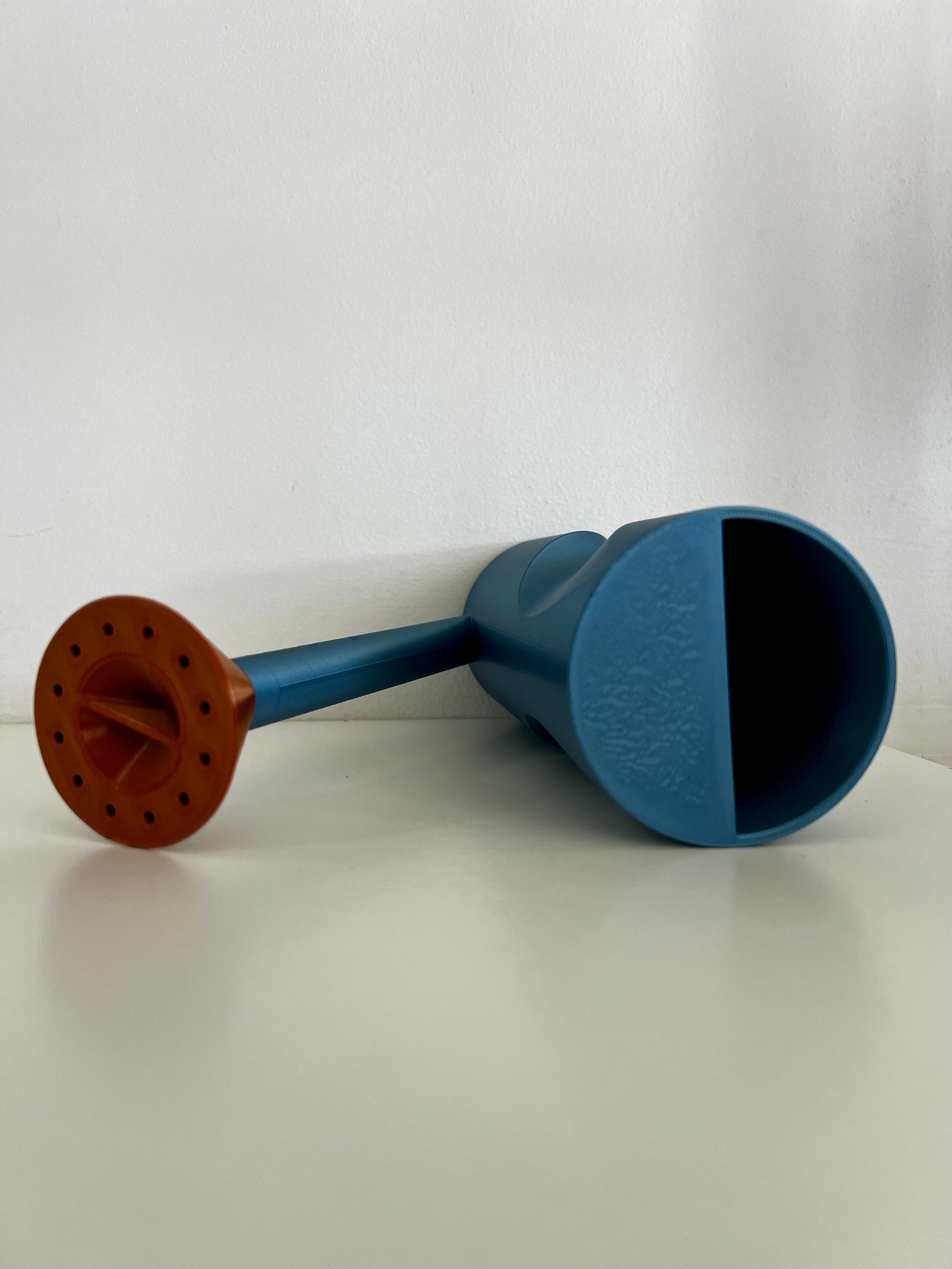 A unique matte black watering can with a copper-spouted design, elegantly displayed on a white surface.