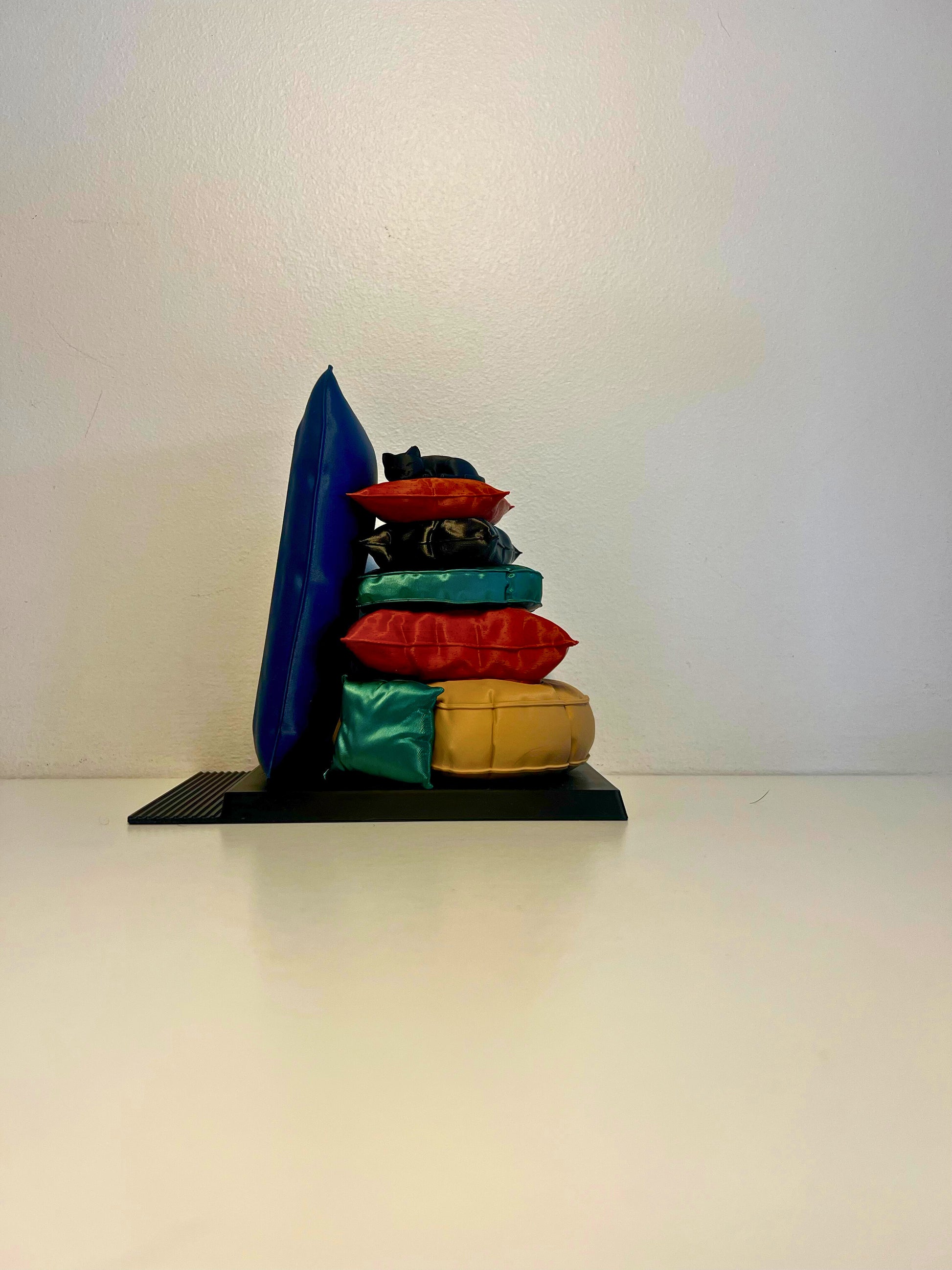 Side view of a playful bookend featuring a stack of colorful pillows with a curled-up cat on top, perfect for book lovers and cat enthusiasts.