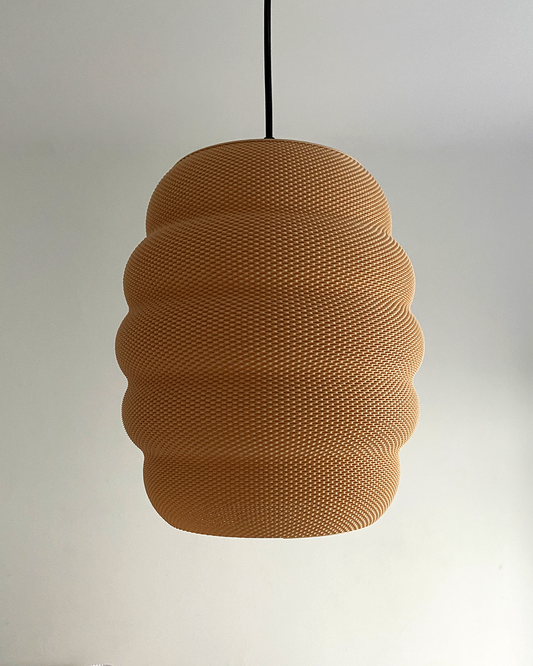 A textured, beehive-shaped pendant light is suspended against a plain white wall, unlit