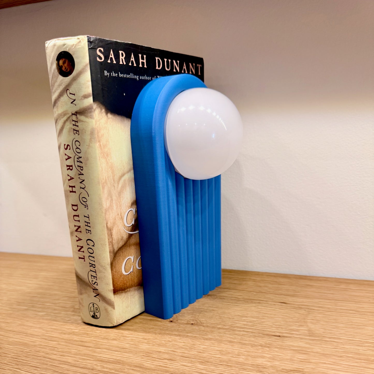 Retro Chic Lighted Bookend for Kids Room or Library showing a blue lighted bookend supporting a book, demonstrating its stylish and practical design.