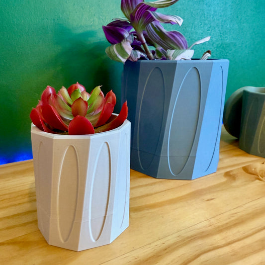 Modern wall-mounted planter with a geometric design, shown in a sleek, single-color finish. Available in 20 vibrant colors.