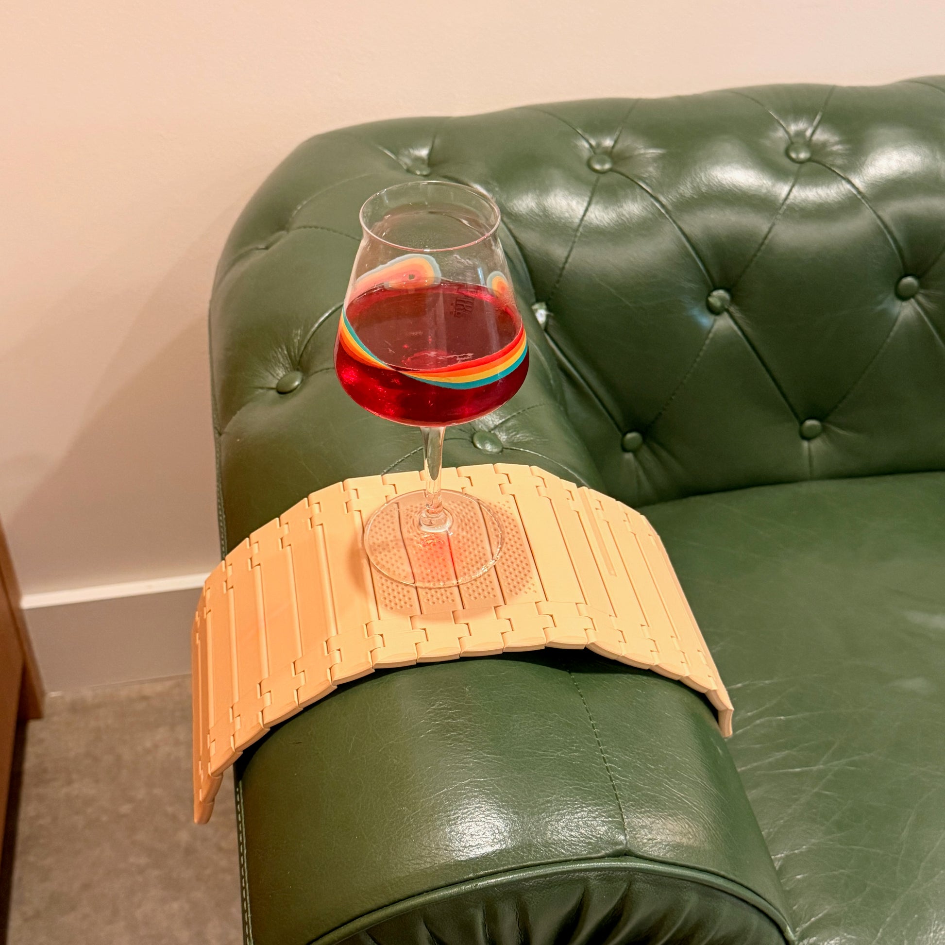 Variegated Monstera Coaster Set resting on an armchair valet, elegantly holding a glass of drink in a cozy setting.