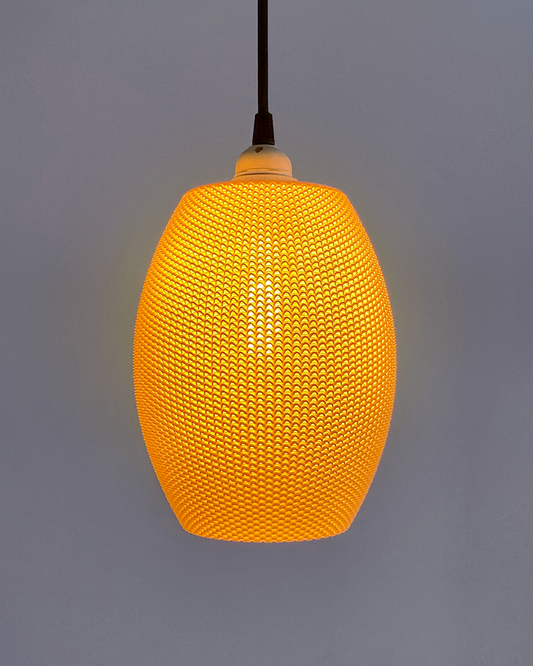 Ovo Lampshade in a warm orange hue, showcasing its elegant oval design, illuminated, offering a cozy atmosphere for modern home décor.