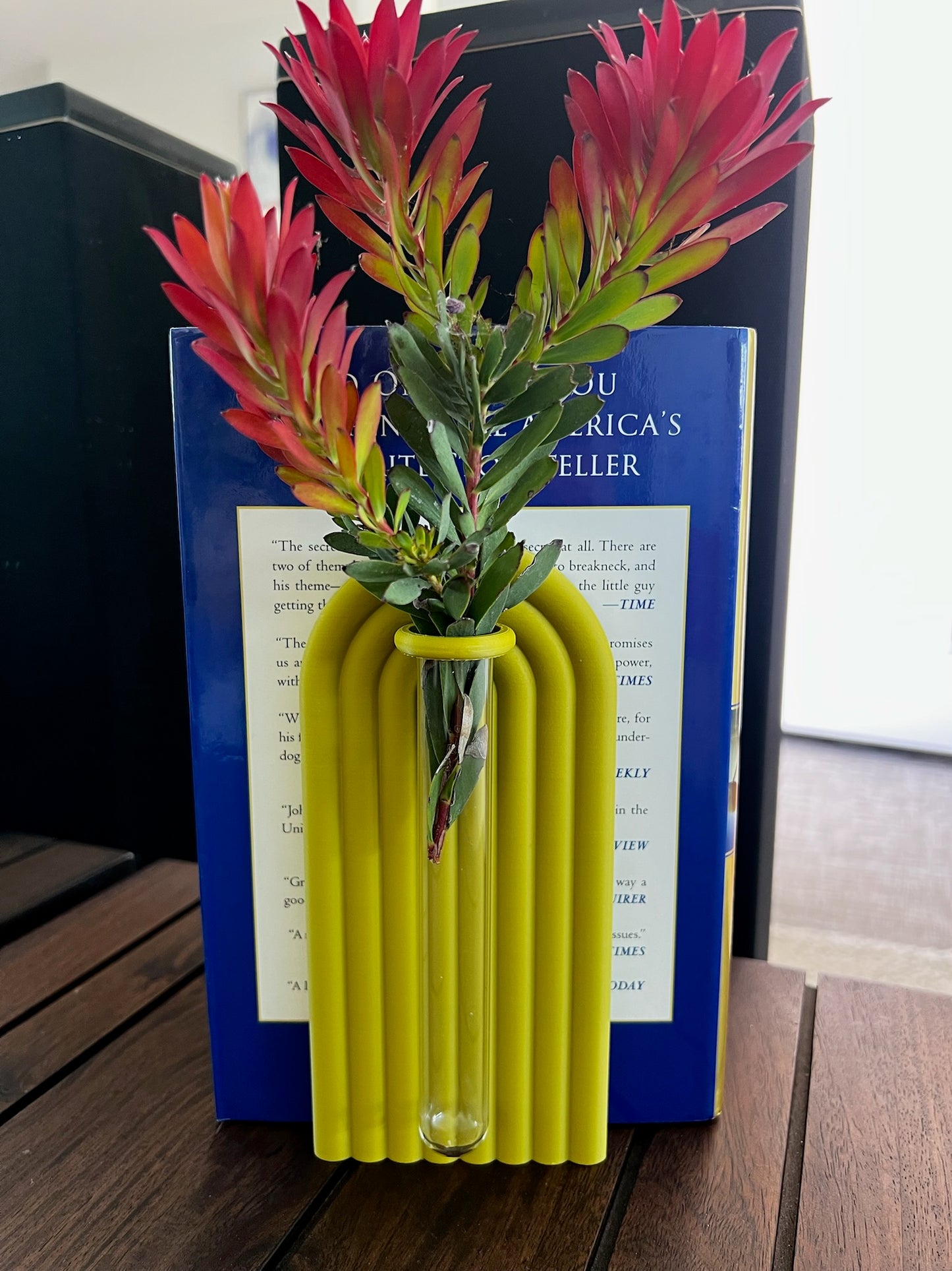 Yellow vase with red flowers against a book background