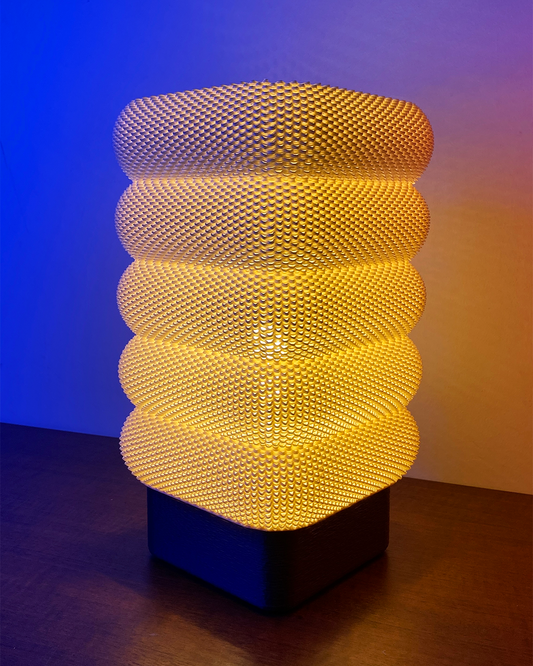 SARA Table Lamp with a modern textured design, glowing warmly against a blue backdrop, showcasing its unique layered shades.