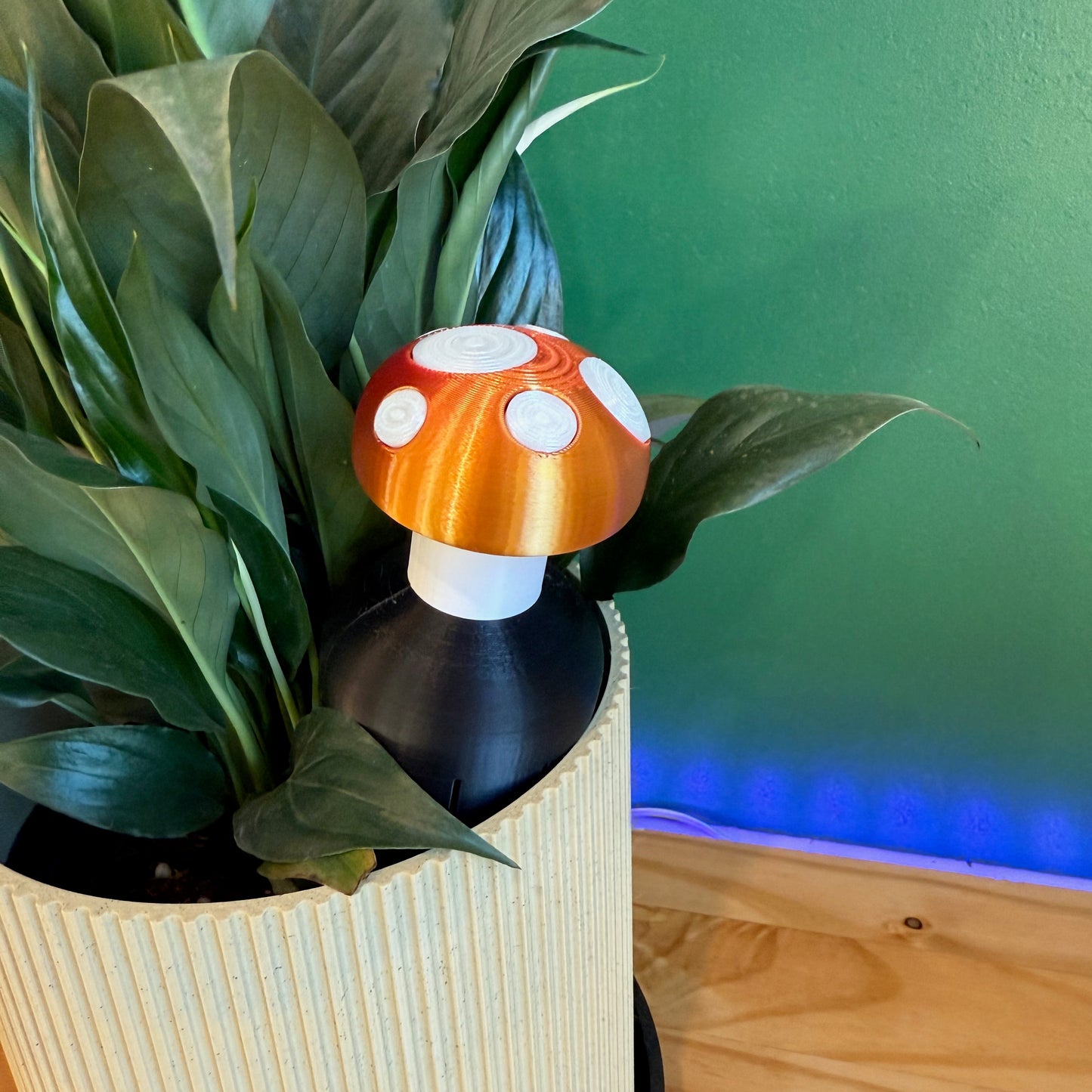 Toadstool Water Spike displayed as a plant watering spike in a decorative planter with lush green leaves.
