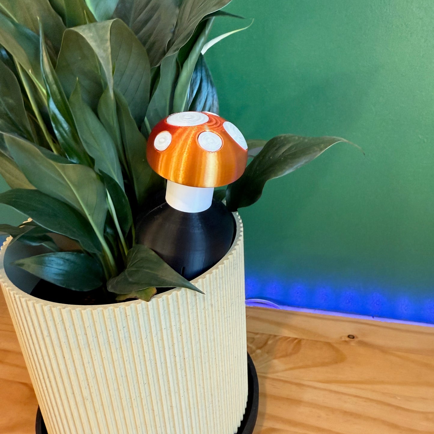 Close-up view of the Toadstool Water Spike acting as a plant watering spike atop a stylish planter surrounded by plants.