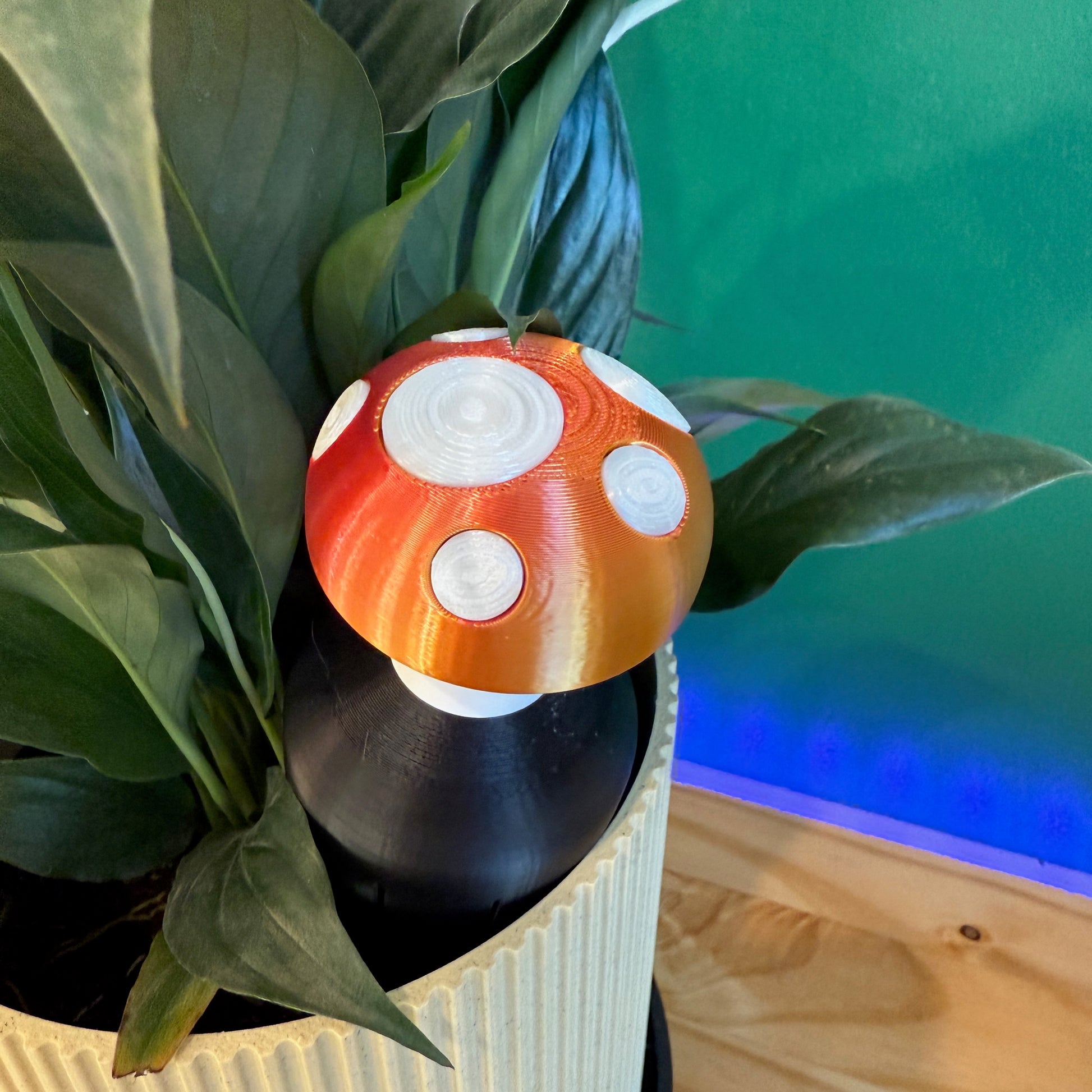 Another angle of the Toadstool Water Spike, showcasing its vibrant design and function as a plant watering spike in a decorative plant pot.