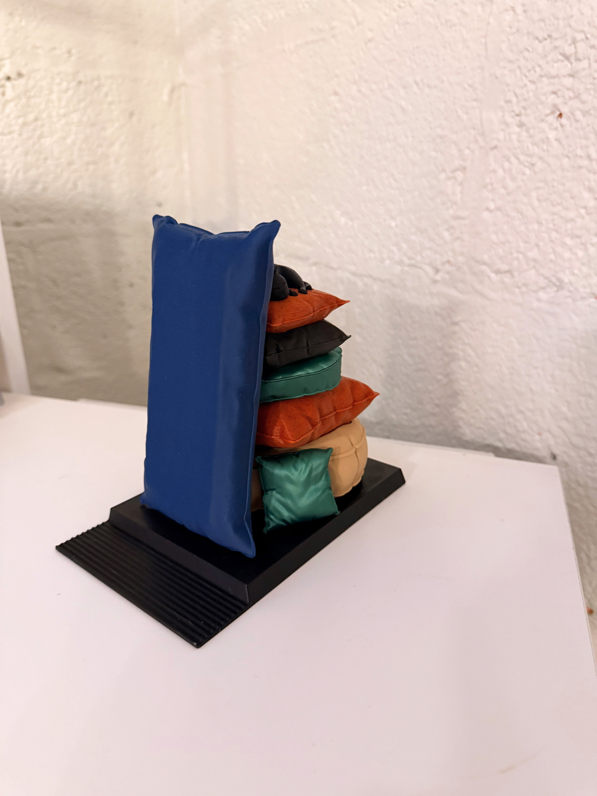 Side view of the Sleepy Cat Bookend displaying a colorful stack of plush pillows, ideal for organizing books while adding a charming touch to decor.